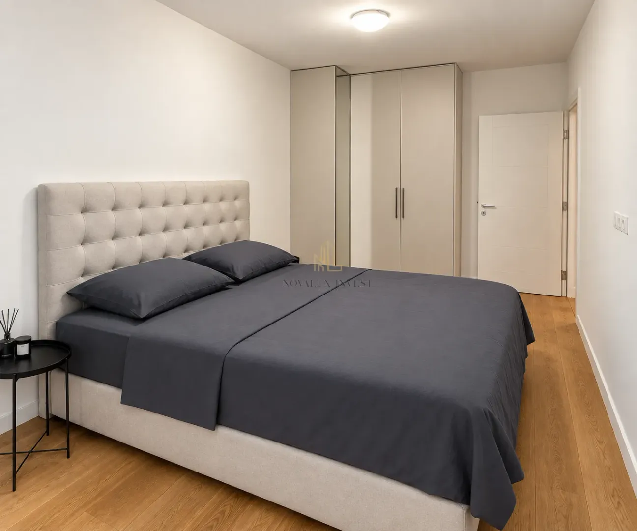 Modern bedroom featuring a double bed, wardrobe, and wooden flooring.