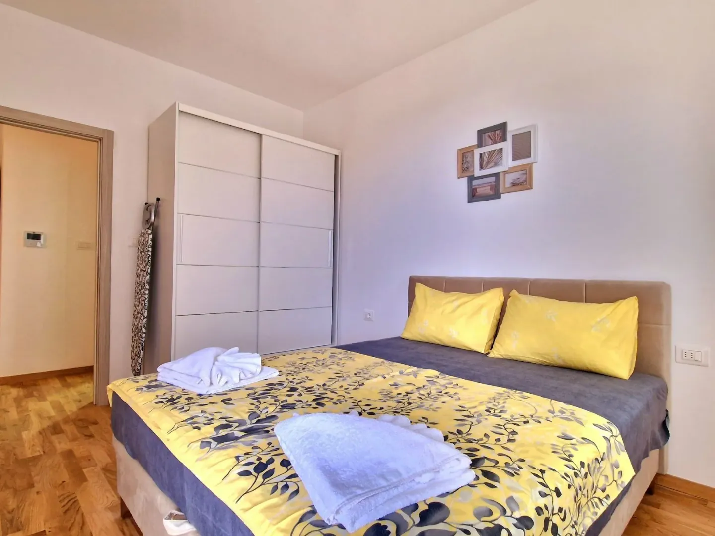 Bedroom with a double bed, a white wardrobe, and a wooden floor.