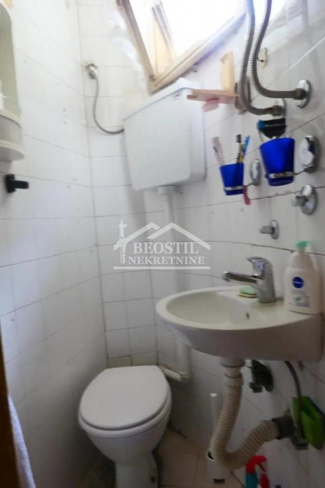 Manje kupatilo sa sanitarijama i belim pločicama.