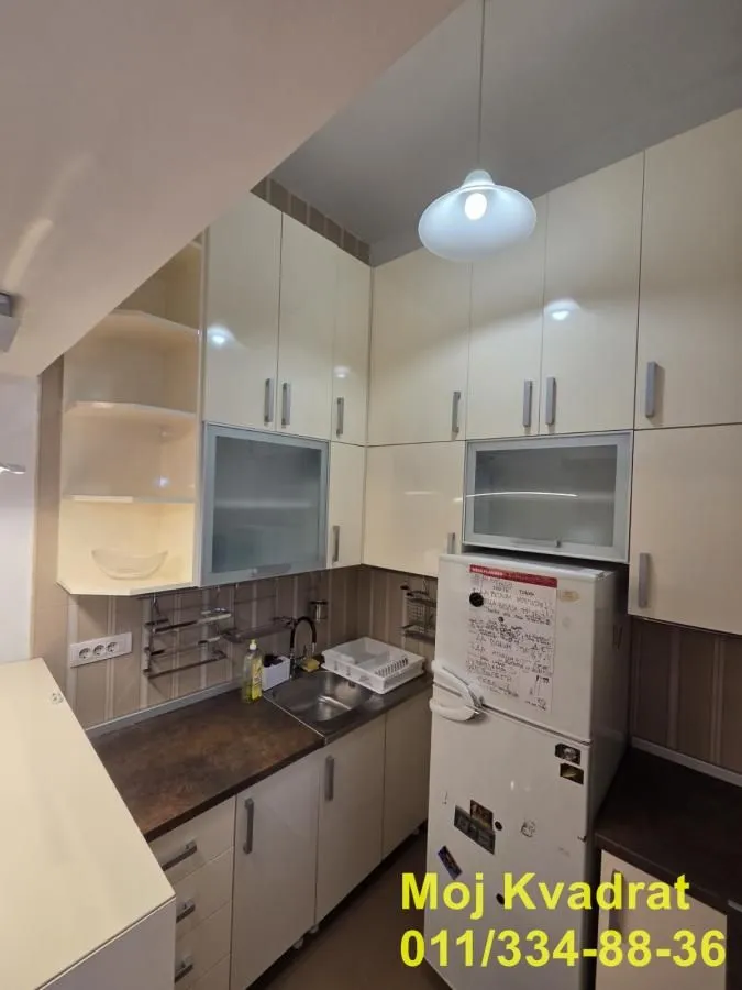 Manja kuhinja sa belim elementima i frižiderom.