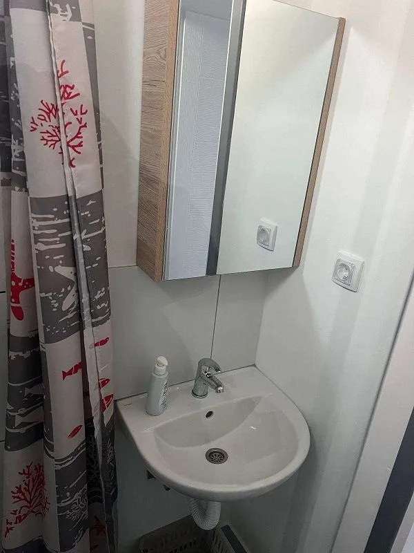 Small bathroom with a sink, mirror, and shower curtain.