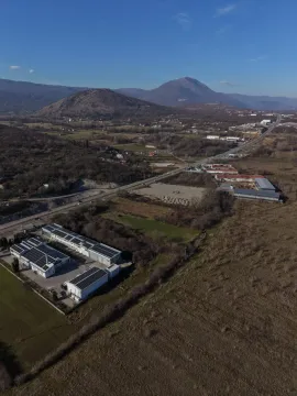 Pogled iz vazduha na industrijski objekat i okolno zemljište sa planinama u pozadini. - image 7