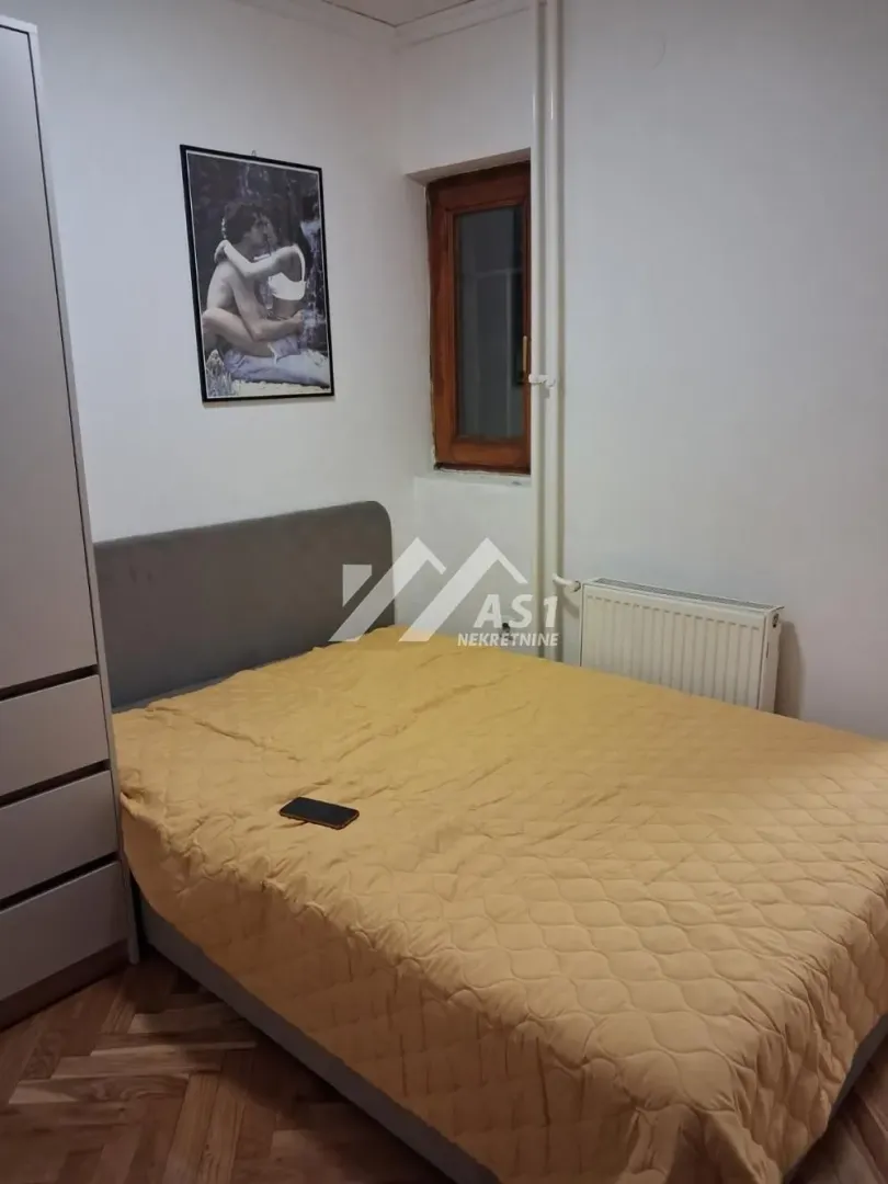 Nameštena spavaća soba sa bračnim krevetom i ormarom.