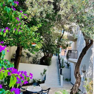 Green courtyard with stairs and a seating table. - image 5