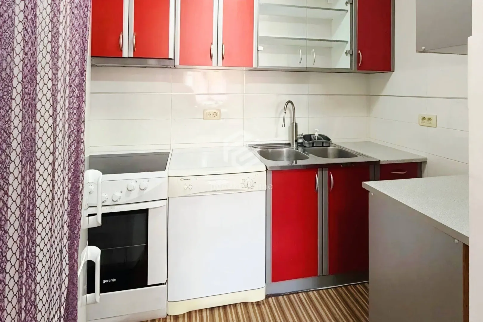 Smaller kitchen with red cabinets, stove, and sink.