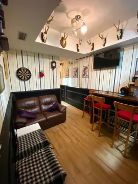 Living room with leather sofa, bar counter, and hunting trophies on the wall. - image 6
