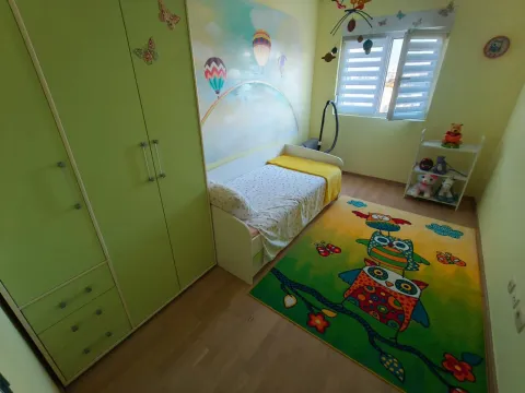 Dječja soba sa krevetom, zelenim garderoberom i šarenim tepihom. - image 8