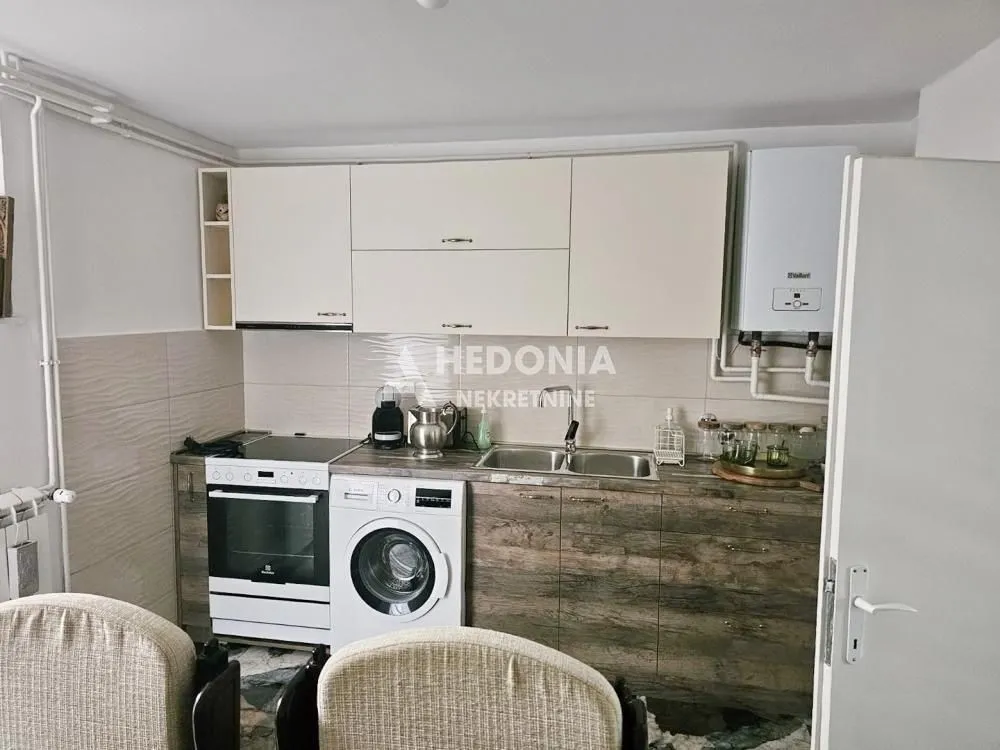 Manja kuhinja sa belim elementima, ugradnim uređajma i sudoperom.