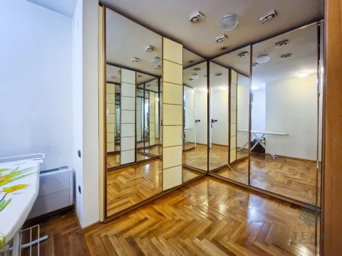 Spavaća soba sa velikim ugradnim plakarom sa ogledalima i drvenim podom. - image 9