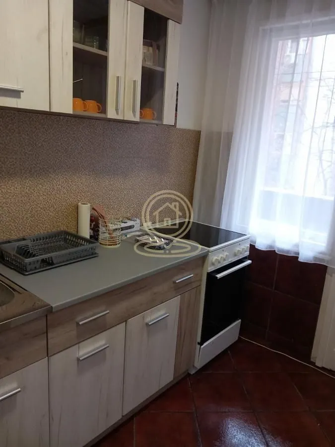 Manja kuhinja sa drvenim elementima i šporetom pored prozora.