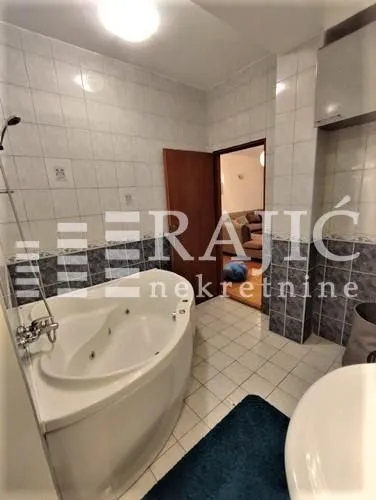 Spacious bathroom with a built-in corner bathtub and tiled walls.