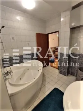Spacious bathroom with a built-in corner bathtub and tiled walls. - image 2
