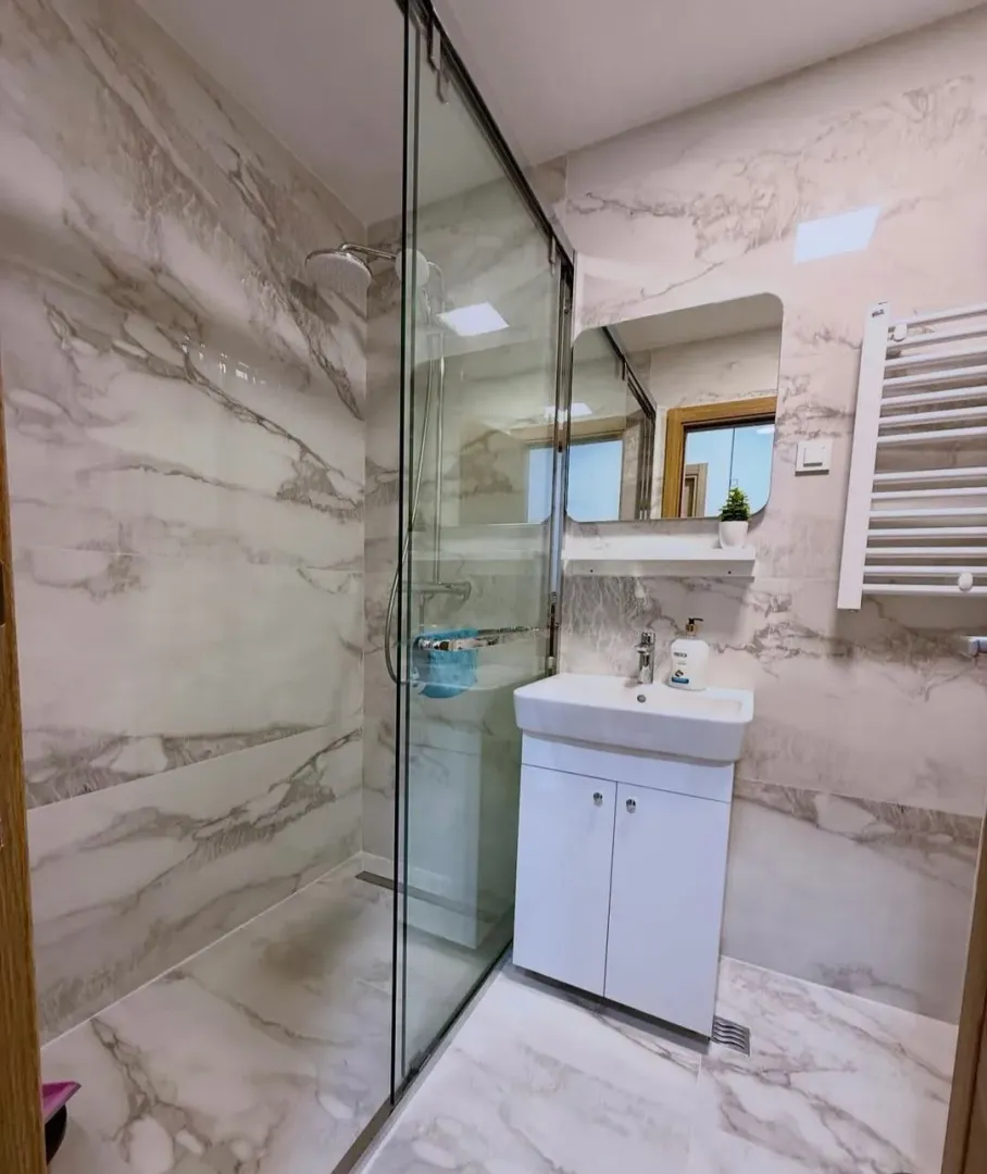 Modernly equipped bathroom with a walk-in shower and marble tiles.