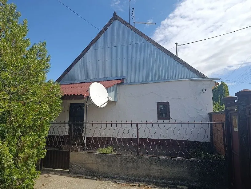 Pogled na spoljašnjost kuće sa dvorištem i ogradom.