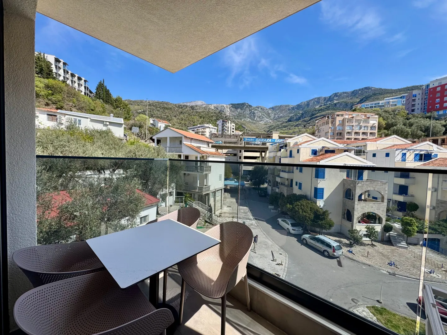 Furnished terrace with a table and chairs and a view of the neighborhood and hills.