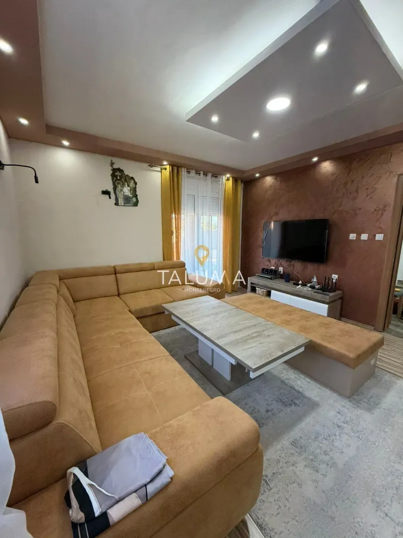 Living room with a large corner sofa and a wall-mounted TV.