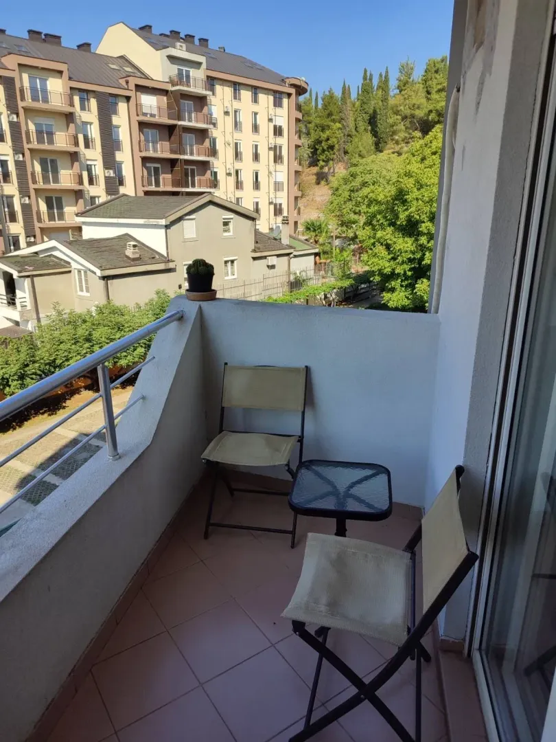 Mali balkon sa dvije stolice i stolom sa pogledom na zgrade.