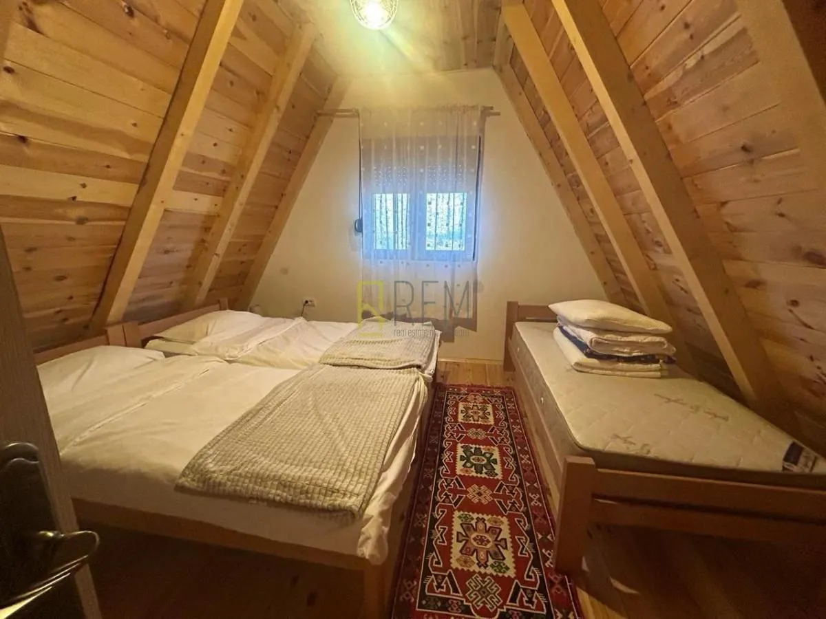 Potkrovna spavaća soba sa drvenim oblogama i dva kreveta.