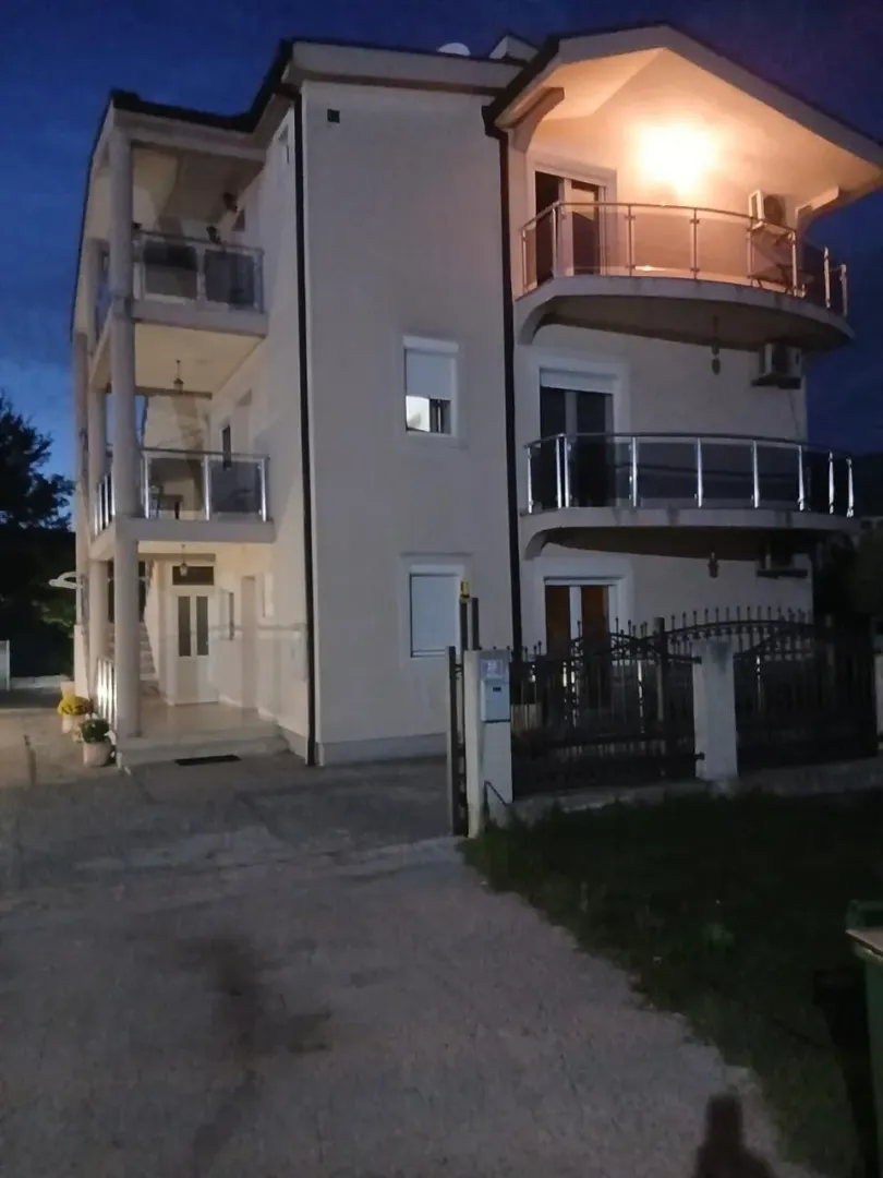 Spoljašnji izgled višespratne stambene zgrade sa terasama u sumrak.