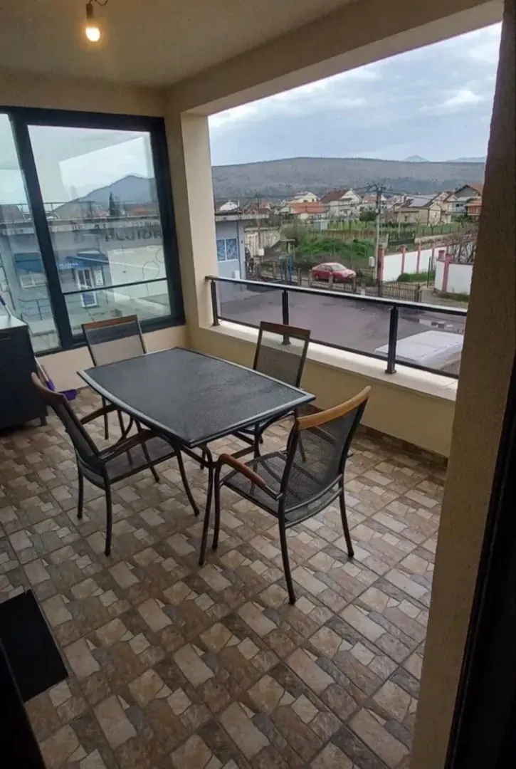 Covered terrace with a dining table and chairs and a view of the surroundings.