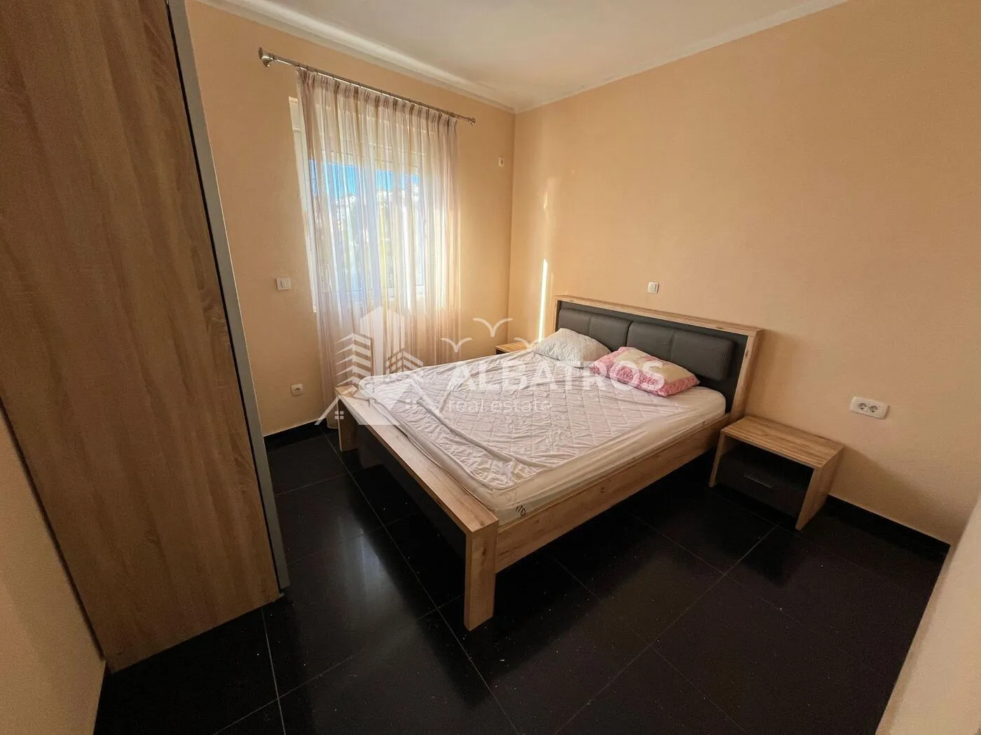 Namještena spavaća soba sa bračnim krevetom, noćnim stočićem i ormarom.