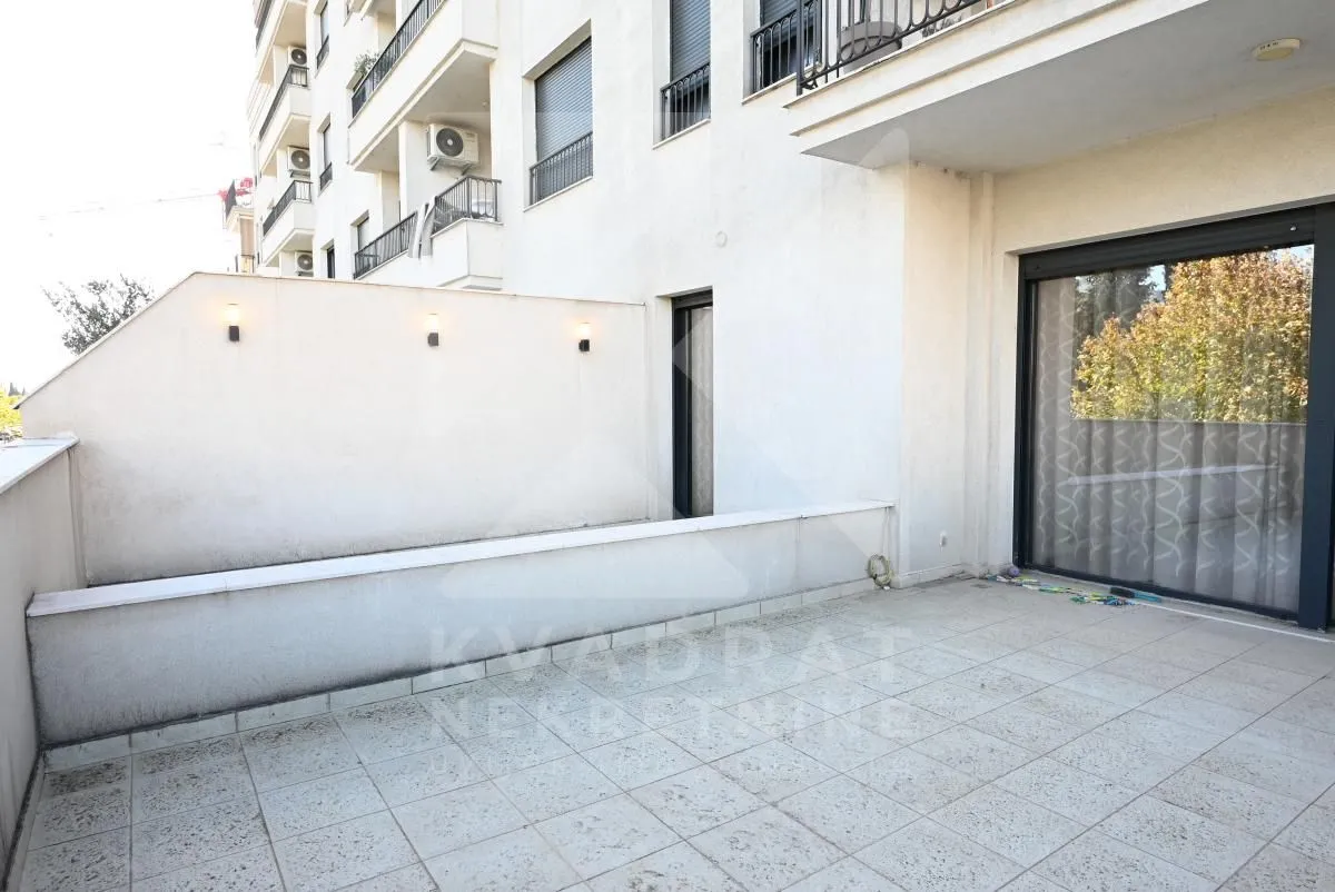 Spacious tiled terrace with wall lighting and access to the apartment.