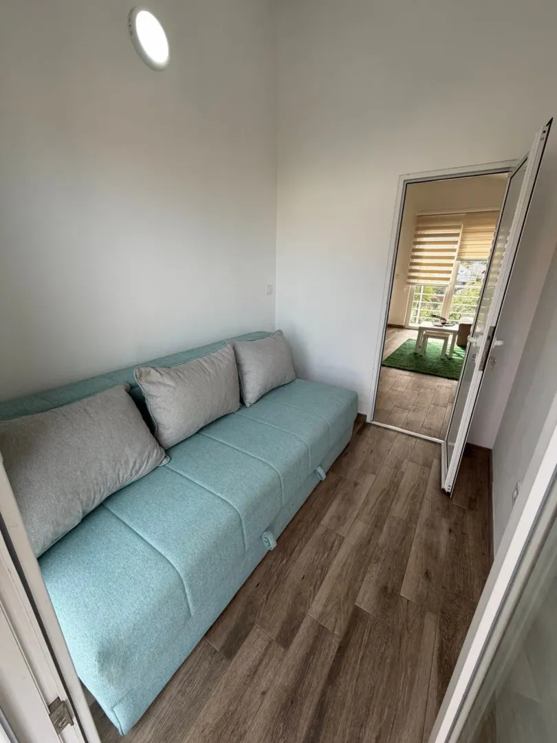 Small living room with a turquoise sofa and a view into another room.