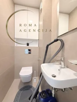 Small bathroom with a toilet, washbasin, and a visible vacuum cleaner. - image 9