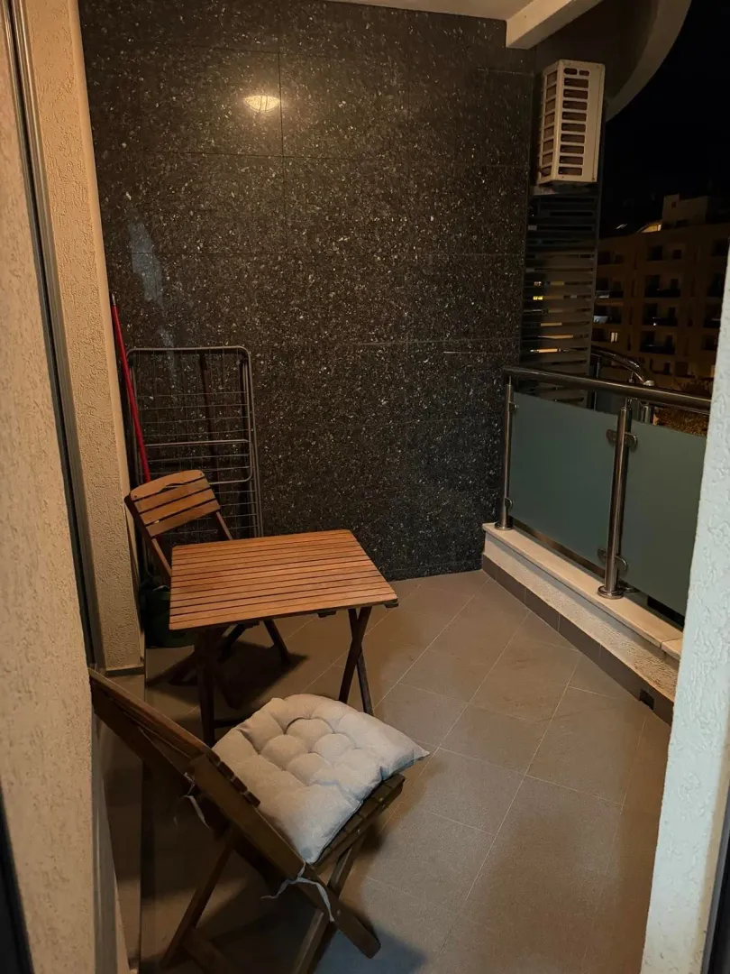 Small balcony with a wooden table and chairs.