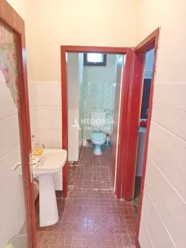 View of the bathroom with a washbasin and a toilet in the extension. - image 8