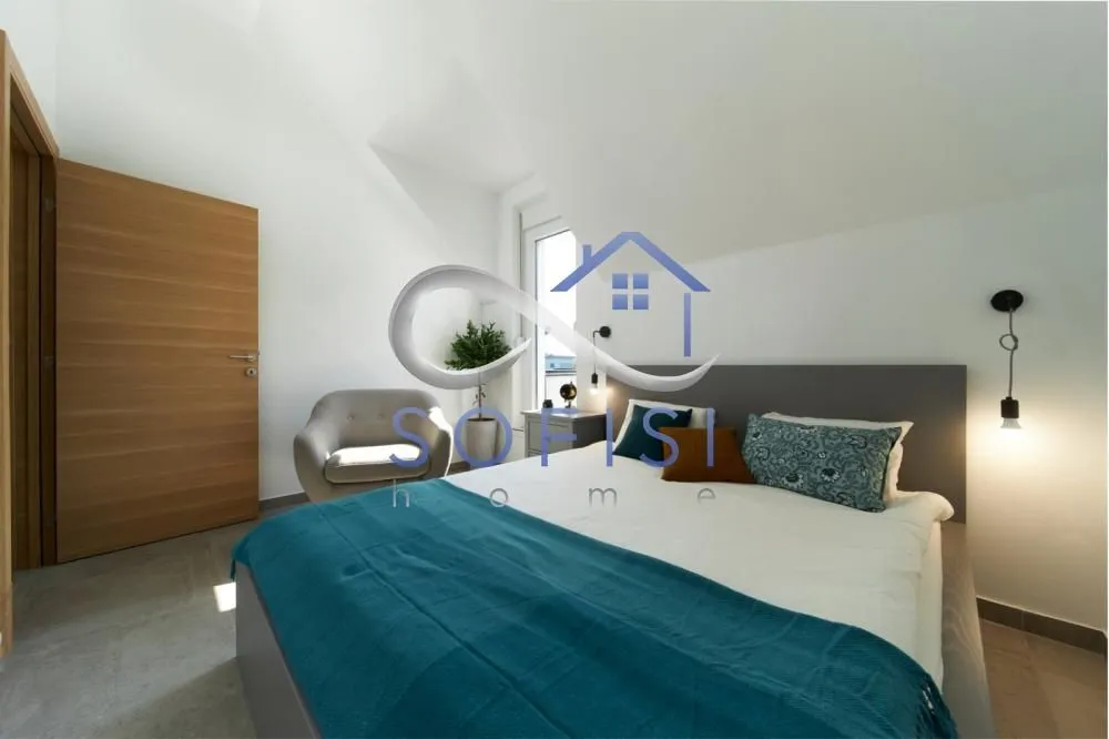 Furnished bedroom with a double bed, armchair, and wooden door.