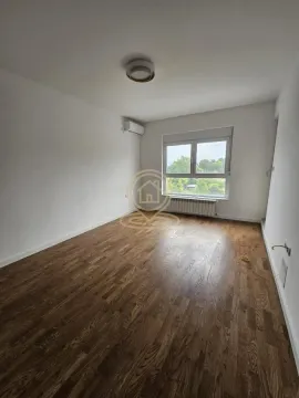 Empty room with wooden flooring, air conditioning unit, and a window overlooking greenery. - image 2