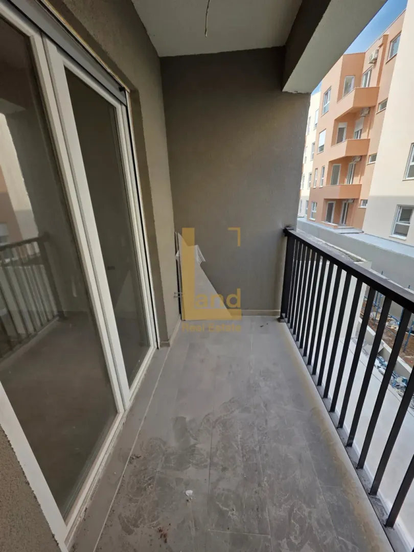Natkriveni balkon sa keramičkim pločicama i pogledom na zgradu.
