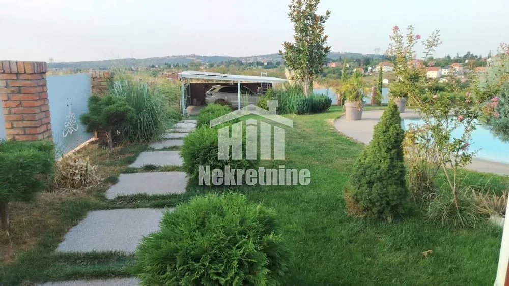View of the landscaped garden with a walkway, greenery, and swimming pool.