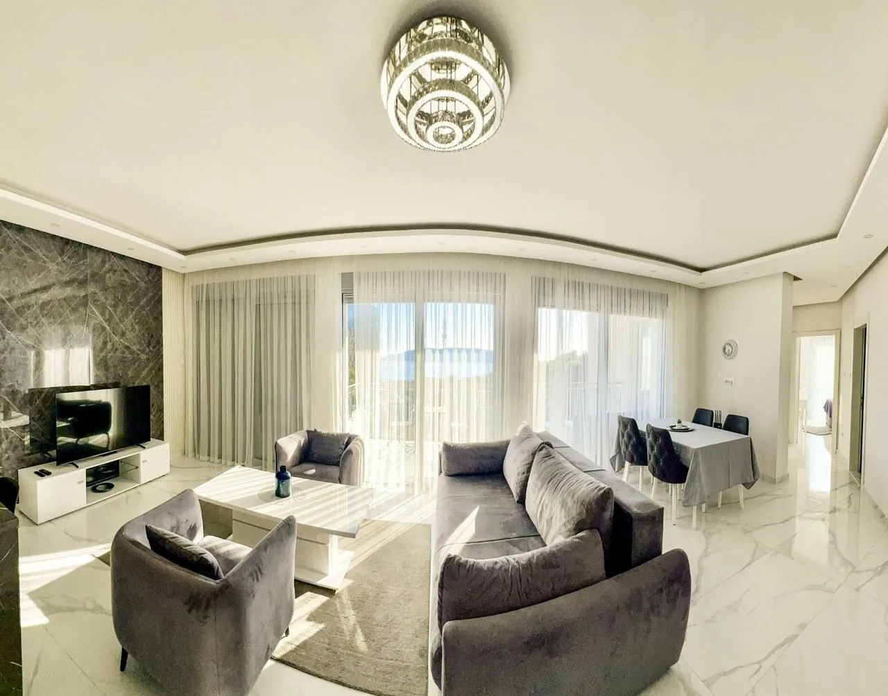 Spacious living room with sofa set, dining area, and access to the terrace.