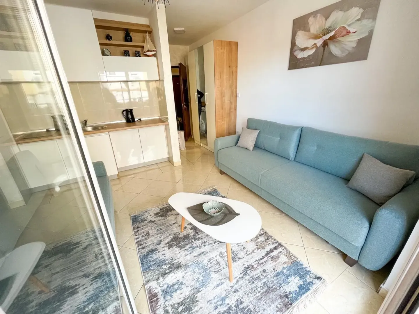 Living room with a sofa and a kitchen in the background.