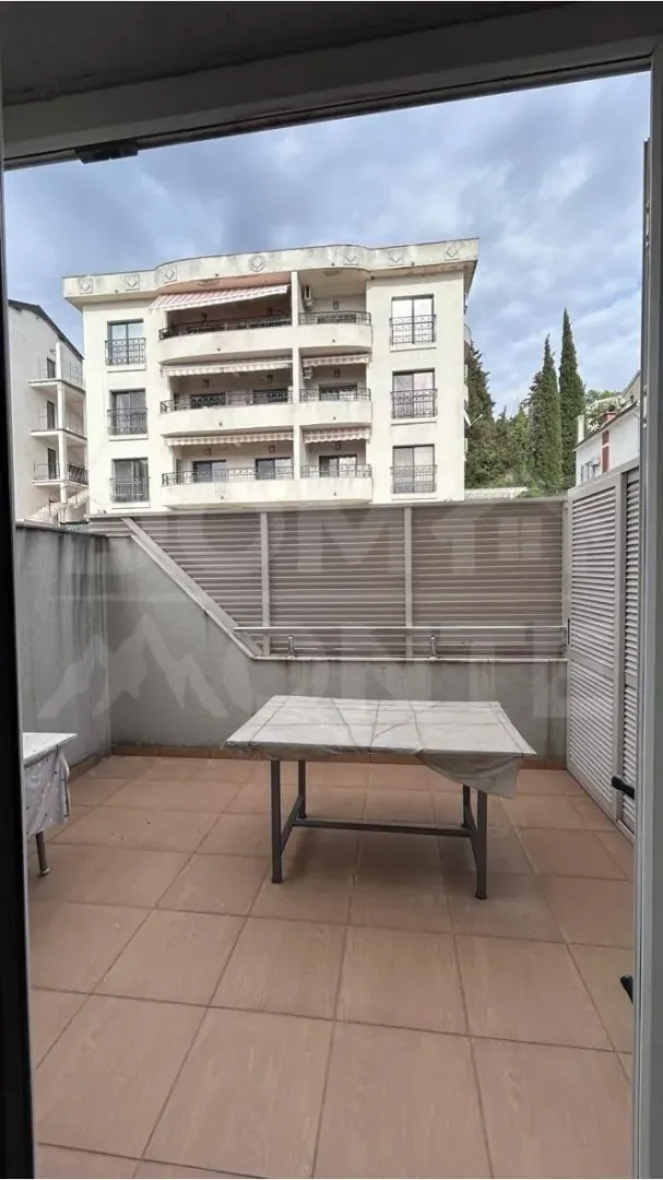 Prostrana terasa sa stolom i pogledom na zgradu.
