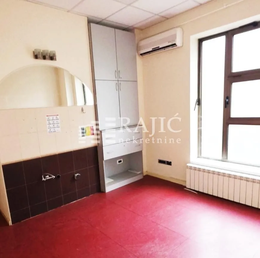 Empty kitchen with fitted units and a red floor.