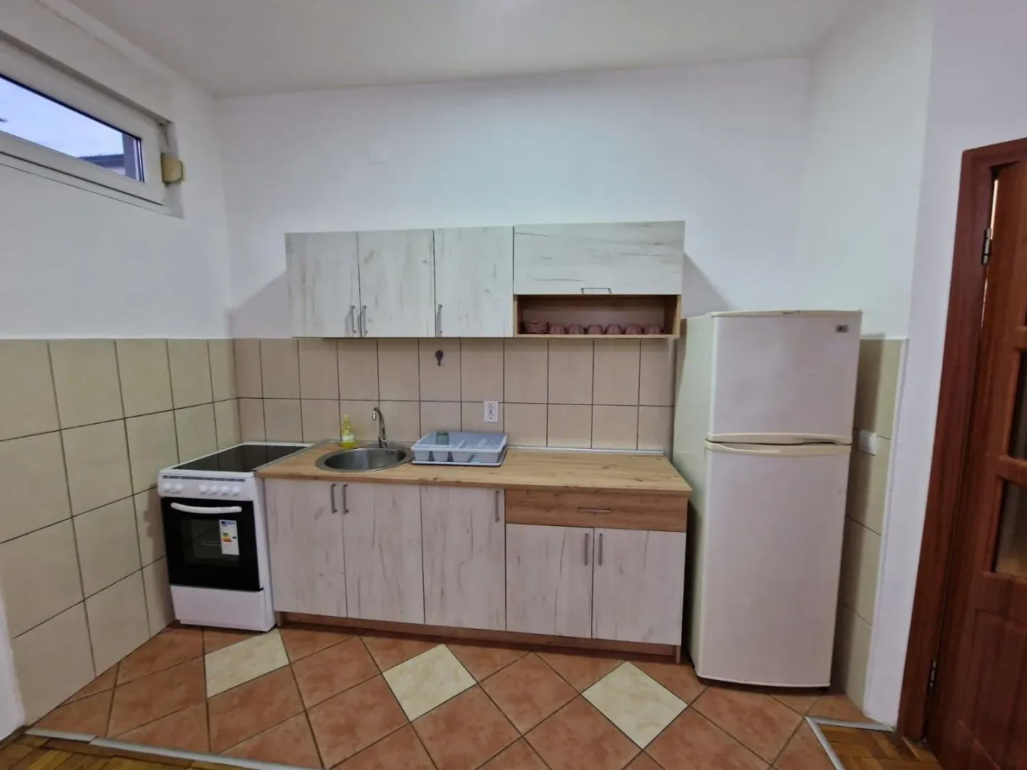 Manja kuhinja sa elementima, šporetom i frižiderom.