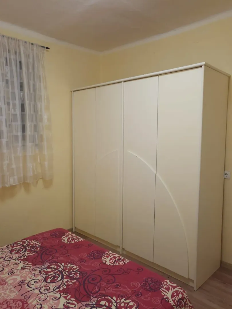 Jednostavna spavaća soba sa velikim ormarom i krevetom.