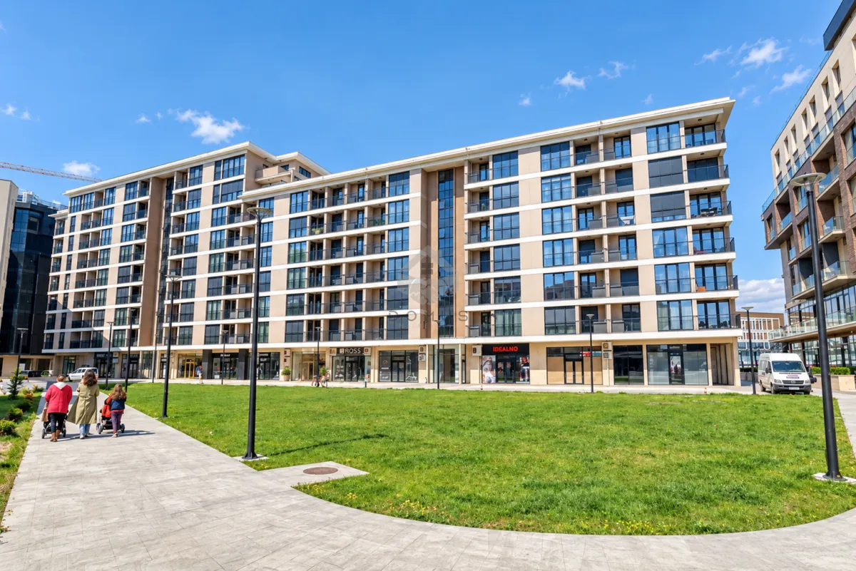 Exterior view of a modern residential building with a landscaped courtyard and walkway.