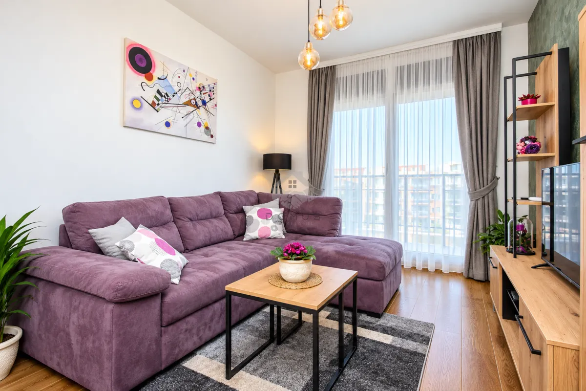 Modern living room with a purple sofa, wooden coffee table, and television.