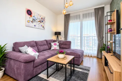 Modern living room with a purple sofa, wooden coffee table, and television. - image 11