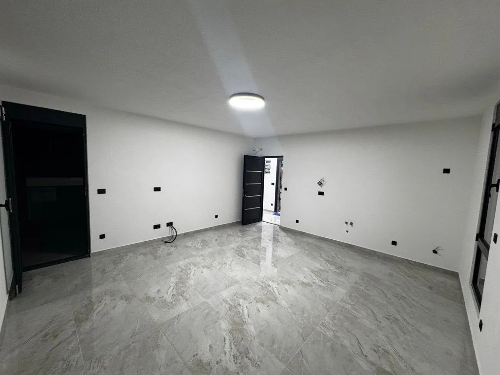 Empty room with glossy floor tiles and white walls.