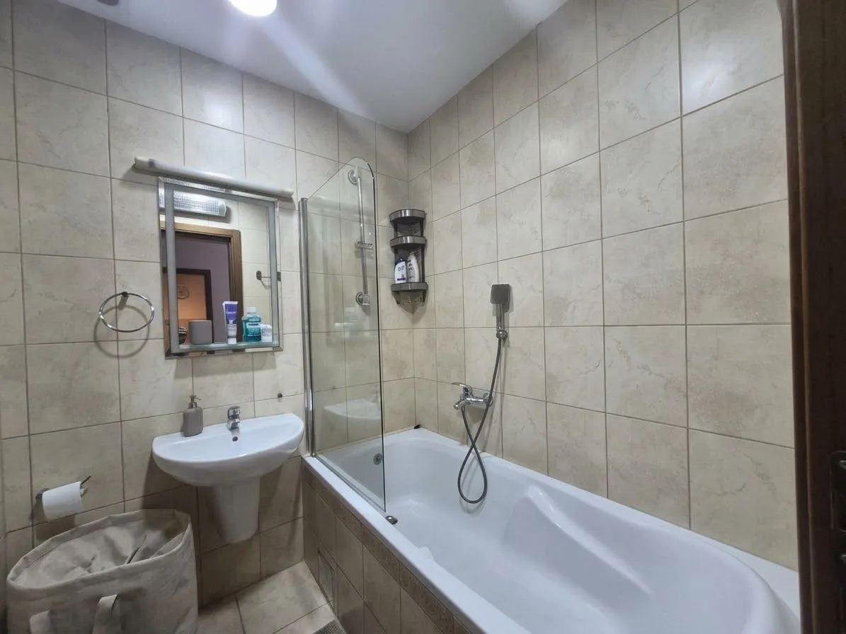 Small bathroom with a bathtub, washbasin, and mirror.