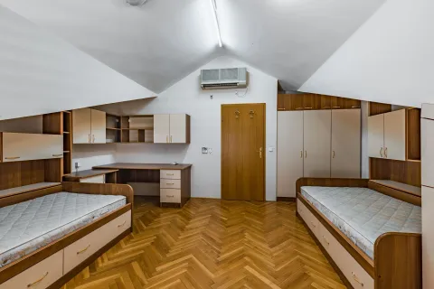 Bright attic bedroom with two single beds and wooden furniture. - image 19