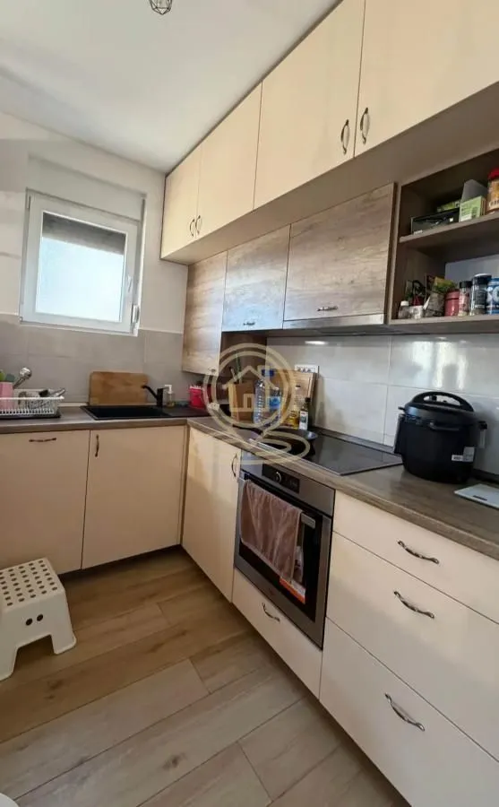 Kuhinja opremljena drvenim elementima i ugradnim kućnim aparatima.