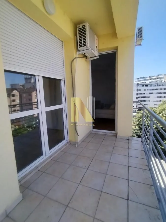 Natkriveni balkon sa popločanim podom i metalnom ogradom.