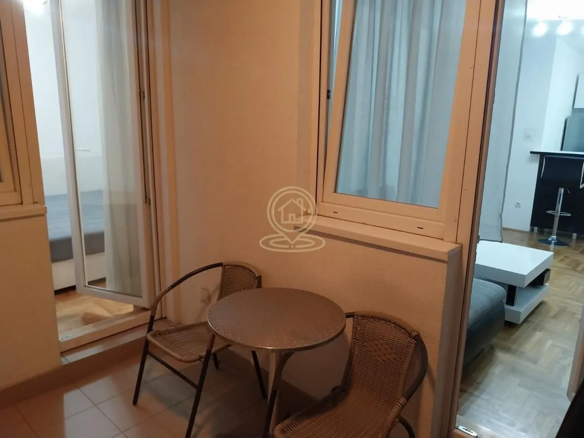 Manji zatvoreni balkon sa stolom i dve stolice.