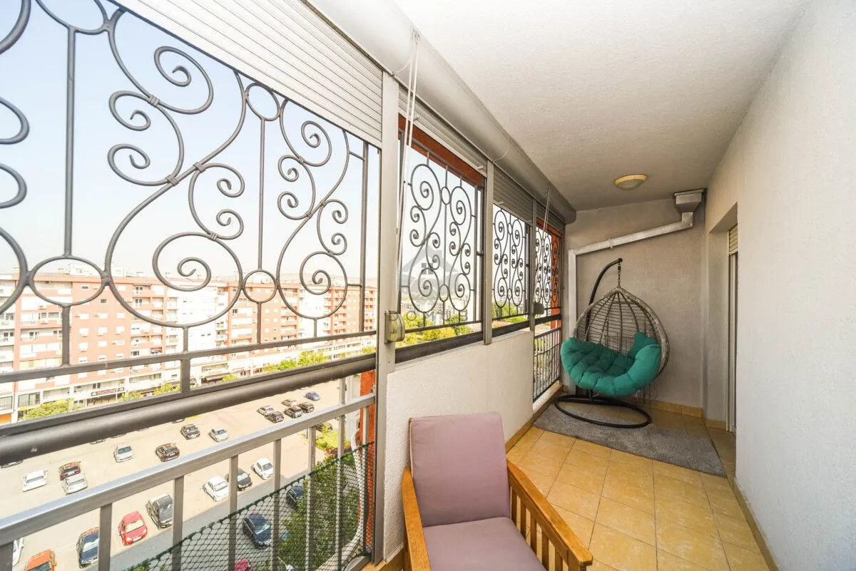 Enclosed balcony with decorative railing and a relaxing armchair.